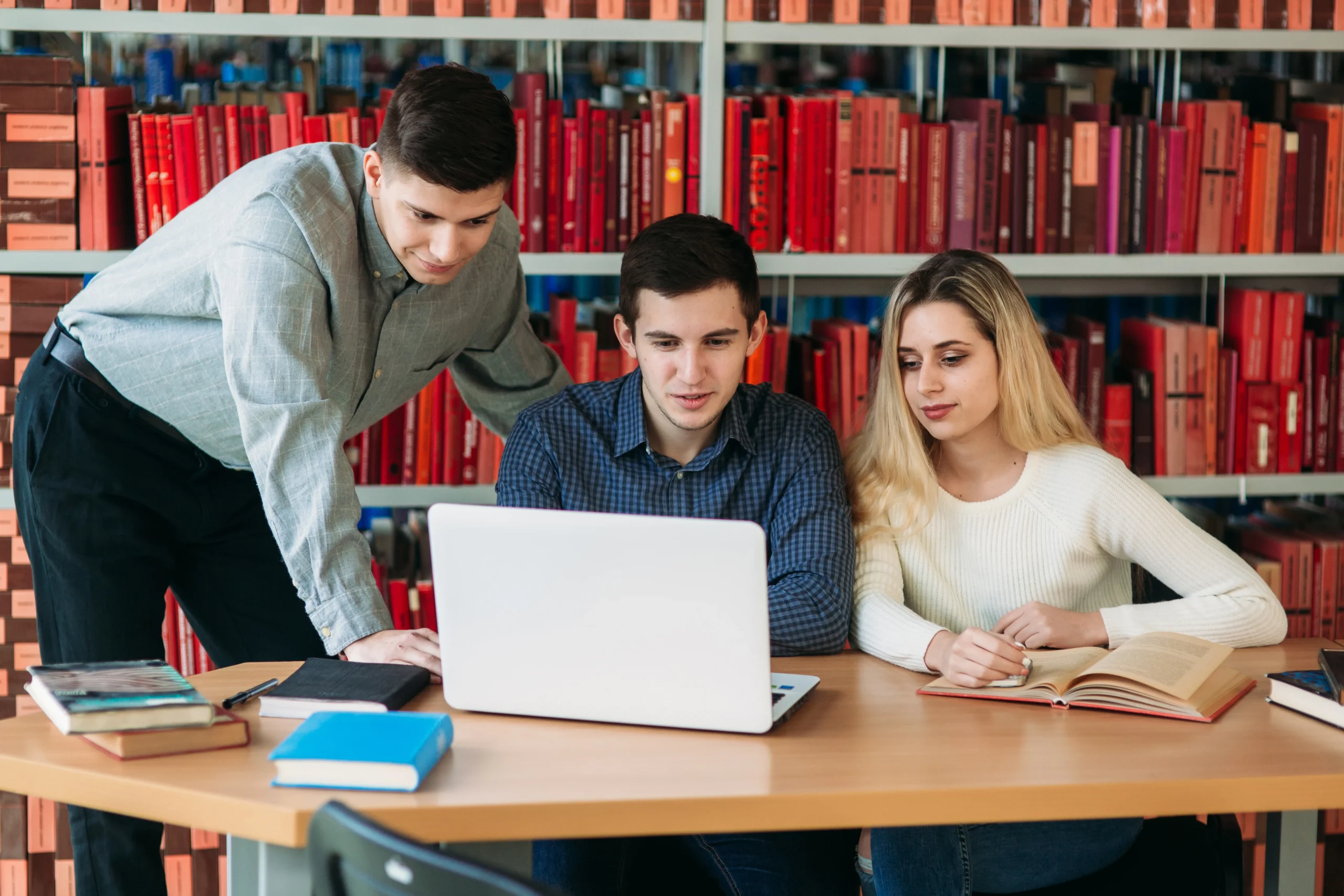 university students sitting together table with books laptop happy young people doing group study library scaled