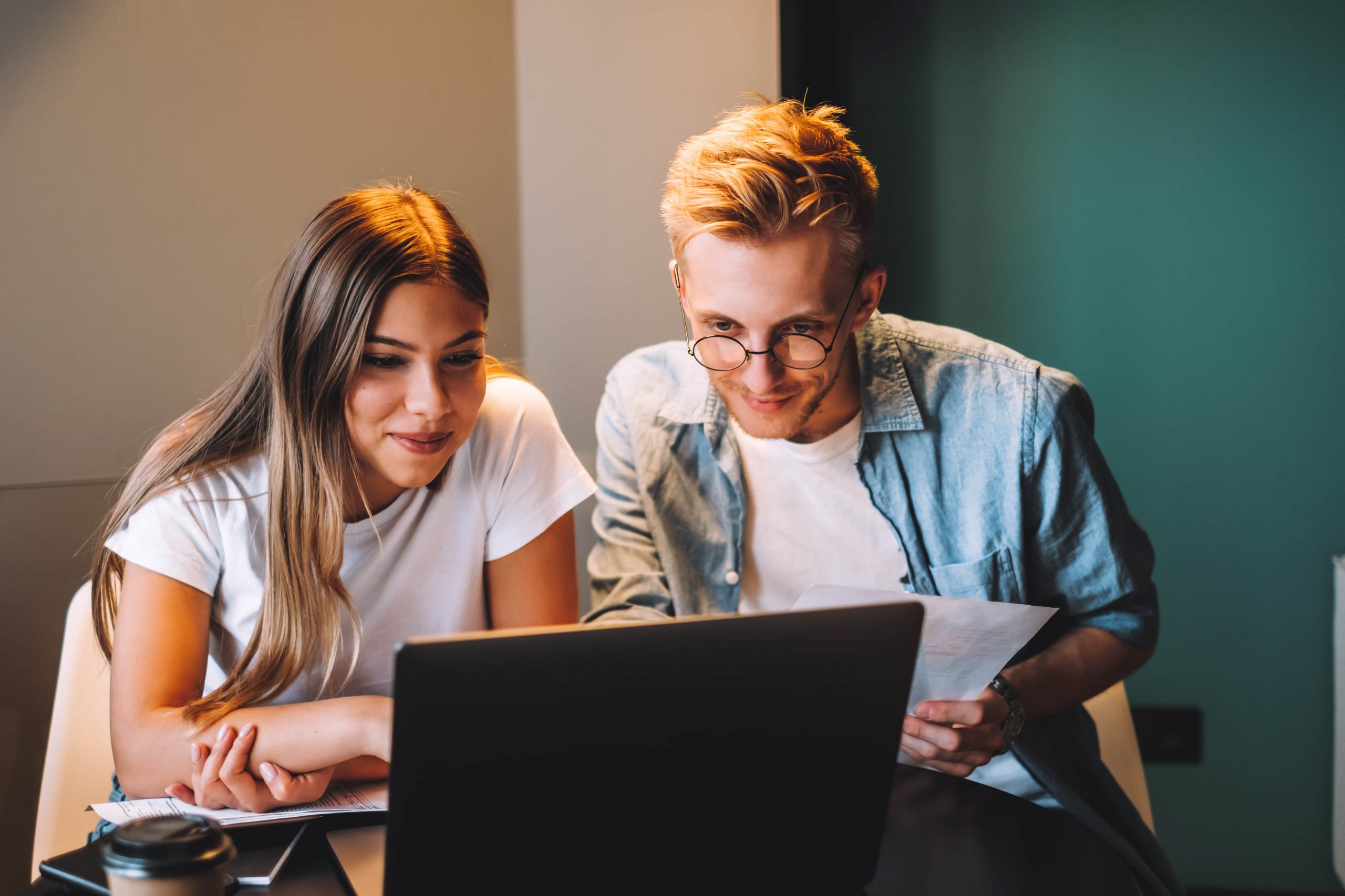 young couple manages finances by looking through their bank accounts desk using laptop scaled